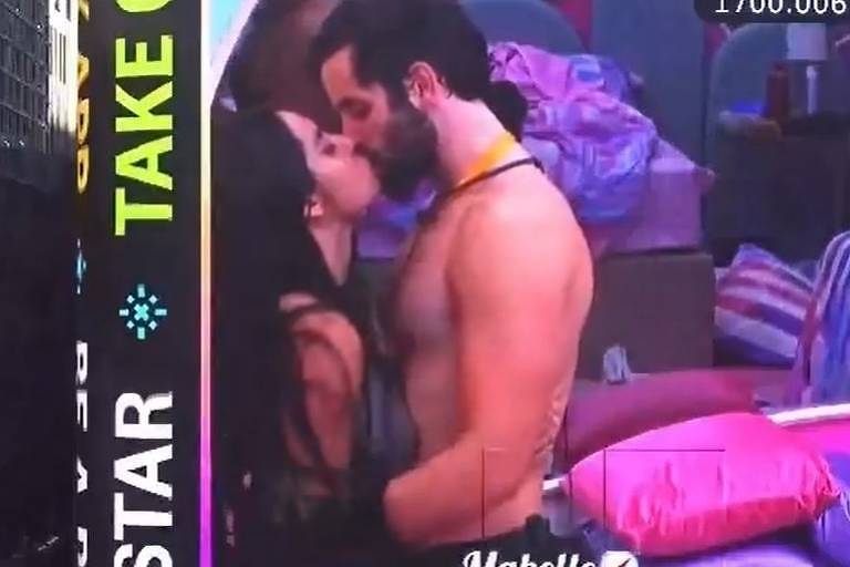 Em foto colorida, casal aparecendo se beijando