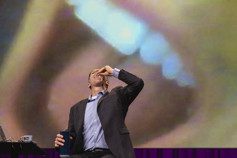 Fotografia de Alex Luebke engolindo uma pílula-robô no palco do TED 2024