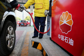FILE PHOTO: A gas station attendant pumps fuel into a customer's car at PetroChina's petrol station in Nantong