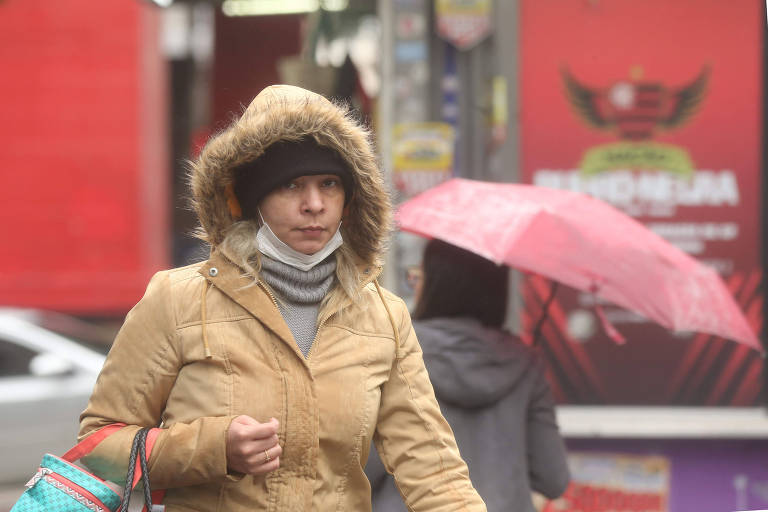 Mulher com casaco e capuz anda pela avenida Paulista, em São Paulo, durante onda de frio