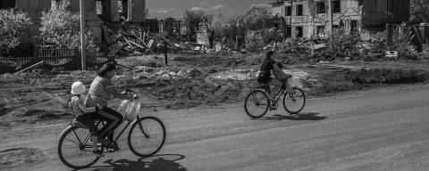 Odessa, Ucrânia - 14/4/2024 - Pessoas passam de bicicleta  por rua de terra batida em meio a casas destruídas por bombardeios no vilarejo de Posad-Pokrovs'ke, Ucrânia. (FOTO: FRANCISCO PRONER/Folhapress) * VENDA SOMENTE NO BRASIL*