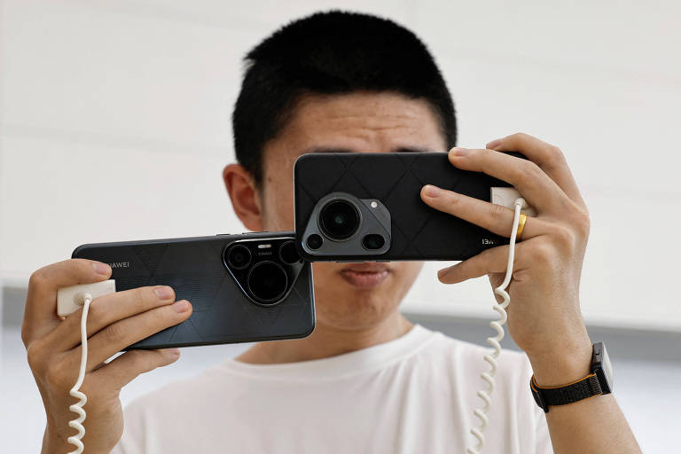 Cliente compara smartphones Huawei Pura 70 Pro e Pura 70 Ultra, em loja em Pequim, na China