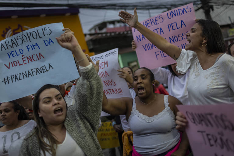 mulheres gritam e gesticulam em protesto, outras pessoas seguram cartazes. é possível ler "PARAISÓPOLIS pelo fim da violência", e paz na favela