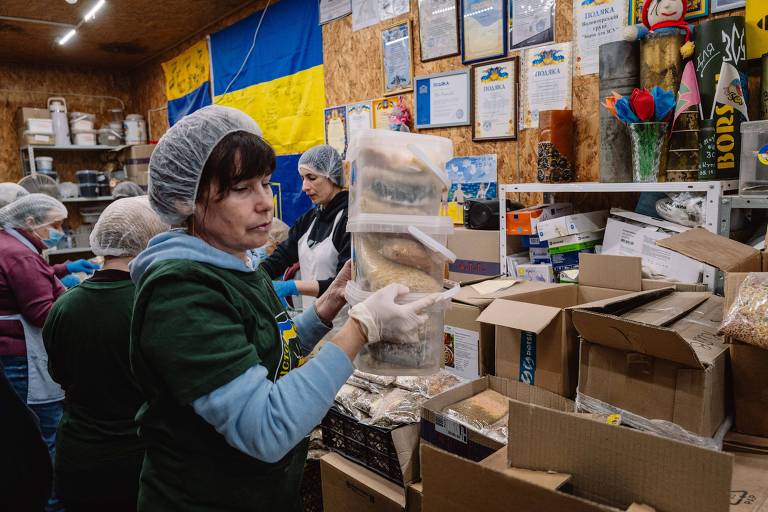 Voluntária carrega pilha de potes com alimentos desidratados na sede do projeto 'Borsht for Victory' em Kiev, na Ucrânia