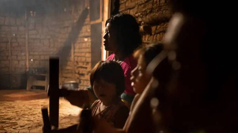 Casal indígena com dois filhos sentados em sua casa