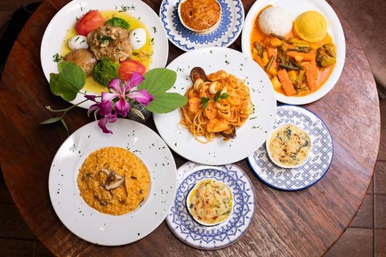 Foto tirada de cima mostra sete pratos de comida portuguesa do restaurante Marialva