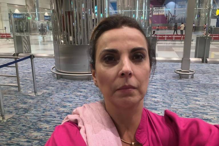 Em saguão de aeroporto, a empresária Marilu Souza, vestida com roupas cor de rosa, olha para a câmera, em foto tipo "selfie"