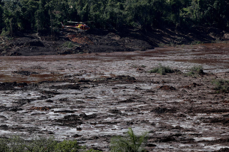 Helicóptero sobrevoa lama despejada após rompimento de barragem