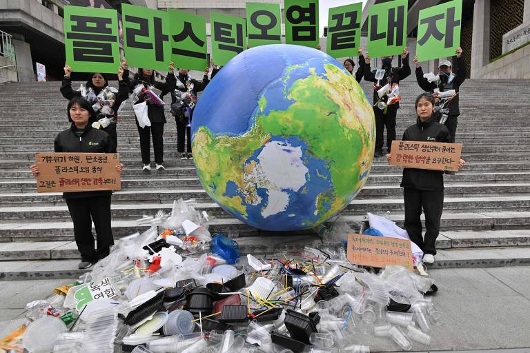 Pessoas seguram cartazes em torno de globo terrestre