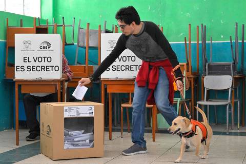 A man casts his vote accompanied by his dog at a polling station during a referendum on tougher measures against organized crime in Quito on April 21, 2024. Ecuadorans voted Sunday in a referendum on proposed tougher measures to fight gang-related crime. The once-peaceful South American country has been grappling with a shocking rise in violence that has seen two mayors killed this week. (Photo by Rodrigo BUENDIA / AFP)