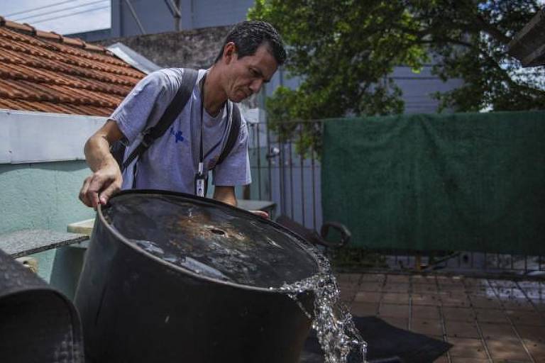 Homem esvazia caixa d'água, possível foco de dengue
