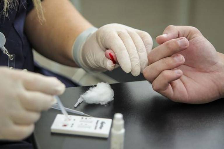 Pessoa tem o dedo picado para realização de teste da dengue