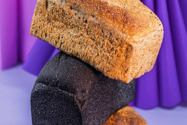 Três pães diferentes estão um em cima do outro. O do meio é pão preto.