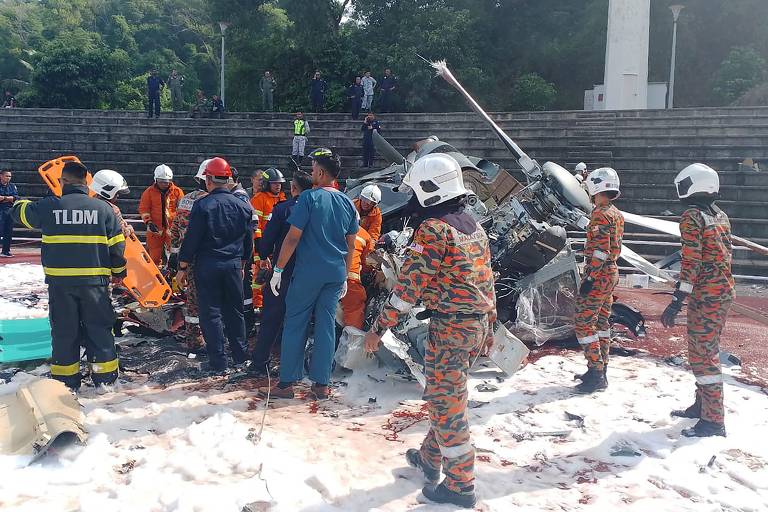 Imagem mostra equipes de resgate inspecionando local do acidente após dois helicópteros militares colidiram em Lumut, no estado de Perak, na Malásia, durante uma sessão de treinamento em 23 de abril. Segundo  a agência de resgate do país, todos os 10 tripulantes a bordo morreram, informou a agência de resgate do país