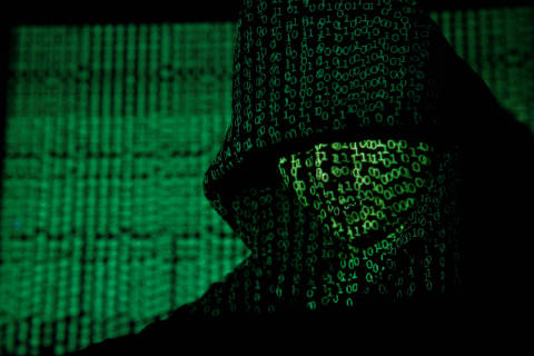 FILE PHOTO: A projection of cyber code on a hooded man is pictured in this illustration picture taken on May 13,  2017. Capitalizing on spying tools believed to have been developed by the U.S. National Security Agency, hackers staged a cyber assault with a self-spreading malware that has infected tens of thousands of computers in nearly 100 countries. REUTERS/Kacper Pempel/Illustration/File Photo ORG XMIT: FW1