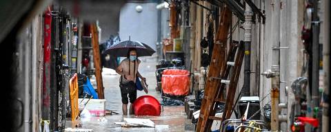 TOPSHOT - A woman walks in a flooded back alley in Hong Kong on September 8, 2023. Record rainfall in Hong Kong caused widespread flooding in the early hours on September 8, disrupting road and rail traffic just days after the city dodged major damage from a super typhoon. (Photo by Mladen ANTONOV / AFP)