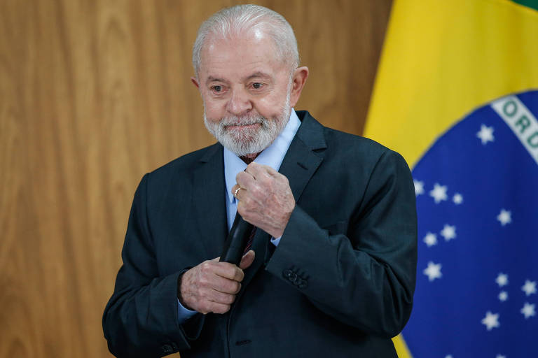 Lula ajeita a gravata enquanto participa de evento no Palácio do Planalto