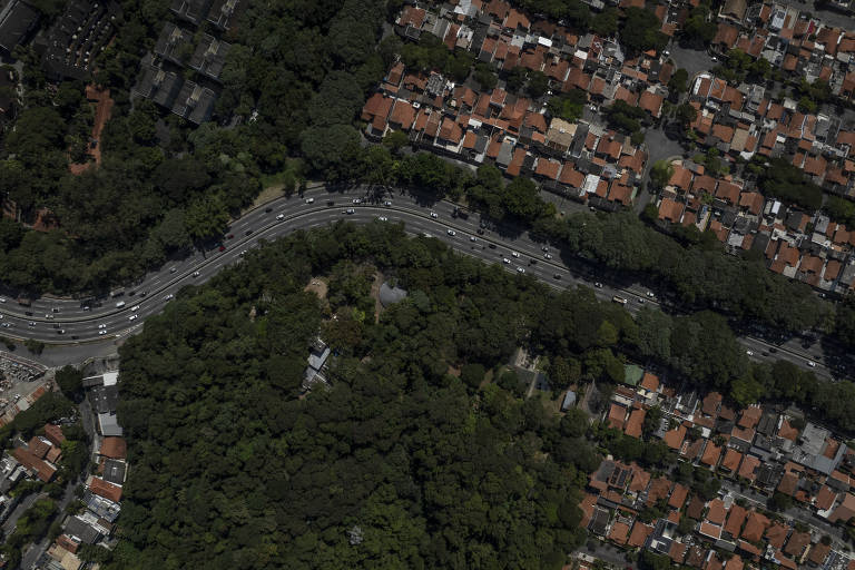 A rodovia passa ao centro, com uma curva no canto esquerdo, onde está uma área repleta de árvores