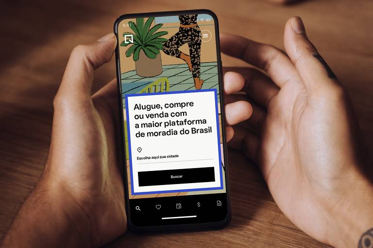 Mão esquerda segurando um celular ligado com escritos "Alugue, compra ou venda com a maior plataforma de moradia do Brasil" na tela