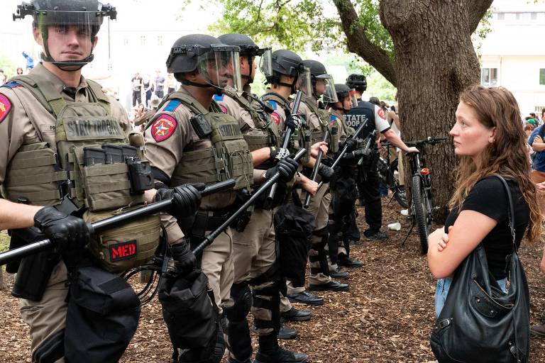 Estudante olha silenciosamente para uma fileira de policiais enquanto estudantes pró-palestinos protestam contra a guerra Israel-Hamas no campus da Universidade do Texas, em Austin