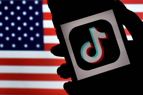 (FILES) In this photo illustration, the social media application logo, TikTok is displayed on the screen of an iPhone on an American flag background on August 3, 2020 in Arlington, Virginia. The US Senate on Tuesday approved legislation requiring the wildly popular social media app TikTok to be divested from its Chinese parent company ByteDance or be shut out of the American market. The measure was part of a $95 billion foreign aid package, including military assistance to Ukraine, Israel and Taiwan, which has now cleared Congress and heads to President Joe Biden's desk. (Photo by Olivier DOULIERY / AFP)