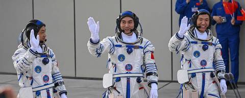 Astronauts for China's Shenzhou-18 space mission (L-R) Li Guangsu, Ye Guangfu and Li Cong wave during a departure ceremony before boarding a bus to take them to the Shenzhou-18 spacecraft at the Jiuquan Satellite Launch Centre in the Gobi desert in northwest China on April 25, 2024. (Photo by GREG BAKER / AFP)