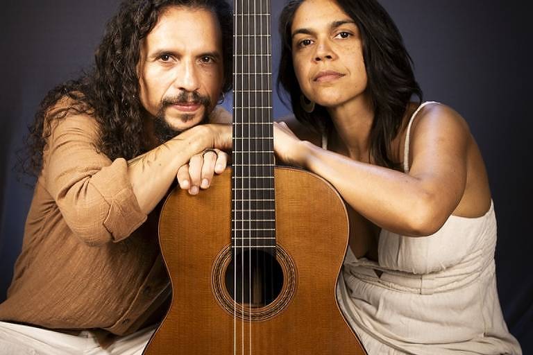 Em foto colorida, o  violonista e arranjador Alex Maia e sua mulher a cantora Carol Andrade posam para a câmera