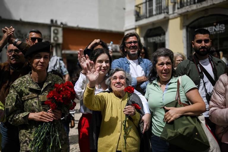 Celeste Caeiro, 90, ao centro, acena durante as comemorações do cinquentenário da Revolução dos Cravos; há 50 anos, ela entregou cravos vermelhos a militares que participaram da revolução