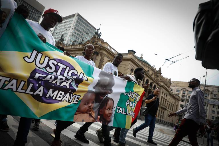 manifestantes carregam faixa com bandeira do brasil com texto "justiça para Mbaye"