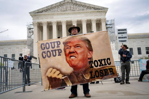 A demonstrator holds a sign outside the U.S. Supreme Court as the justices hear arguments on former President Trump?s claim of presidential immunity over criminal charges over his efforts to overturn the 2020 presidential election results in Washington, U.S., April 25, 2024. REUTERS/Bonnie Cash ORG XMIT: PPP-WAS348