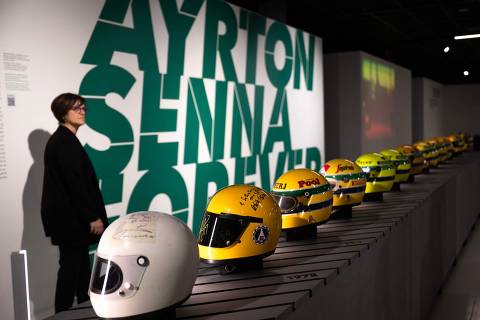 A woman stands near Sennas helmets as she visits the 