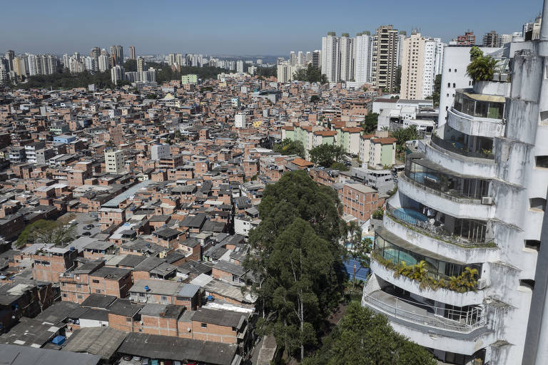 prédio suntuoso com pintura desgastada e manchas de infiltração ao lado de favela
