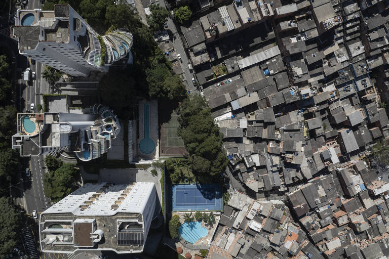 Imagem aérea mostra prédios com piscina cercados por telhados de pequenas casas