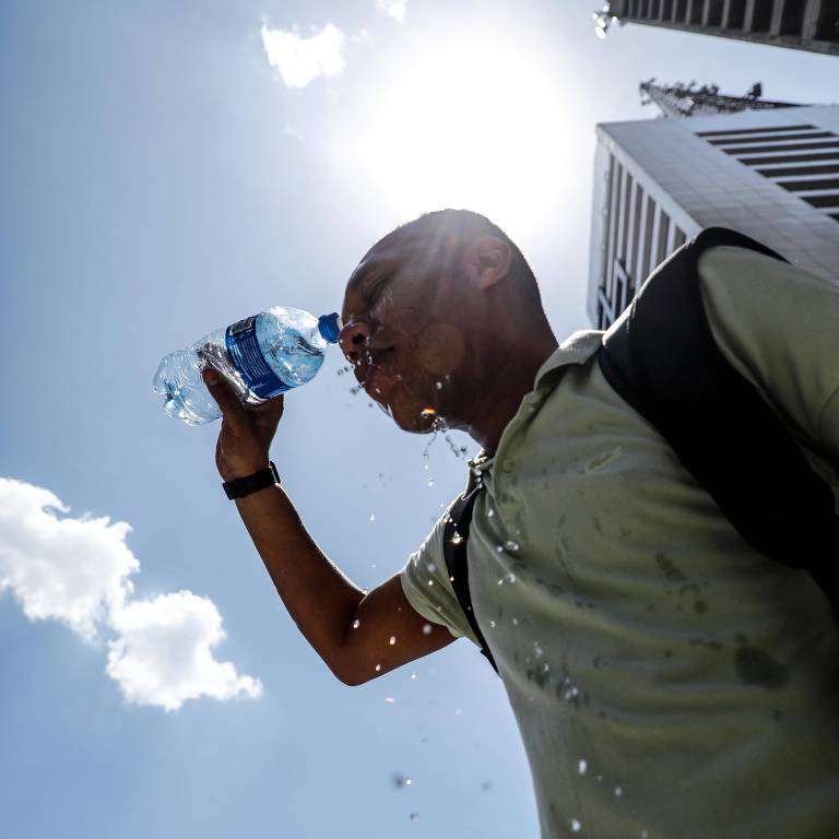 Paulistano joga água no rosto com uma garrafa plástica na região da avenida Paulista, em São Paulo, durante onda de calor de novembro passado; a onda atual chegará a 33ºC até quarta (1º)