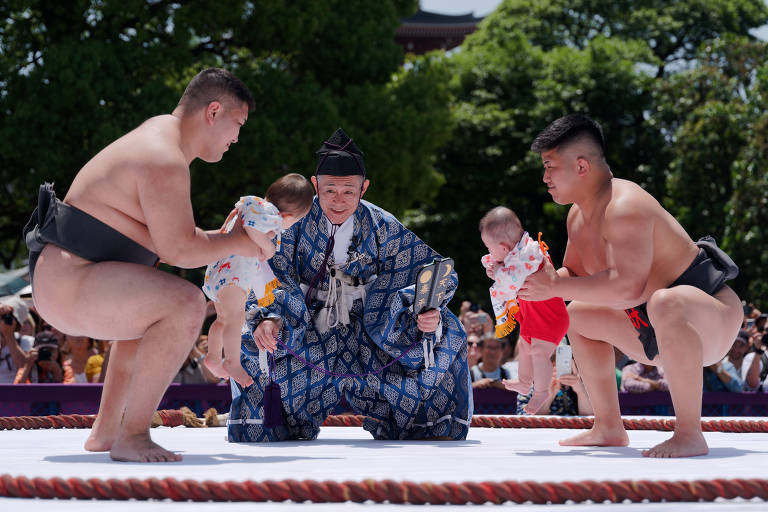 Lutadores de sumô seguram crianças durante o Concurso de Bebês Chorando Naki Sumo em Tóquio, no Japão. O evento Naki Sumo é uma cerimônia tradicional realizada como uma oração por crescimento saudável