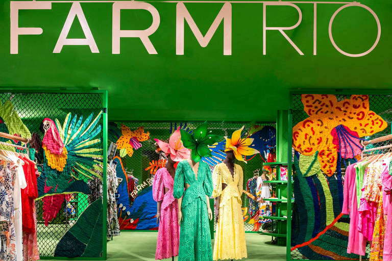 Vestidos de cores fortes, rosa, verde, amarelo, laranja, em estande com paredes verdes e o nome farm rio