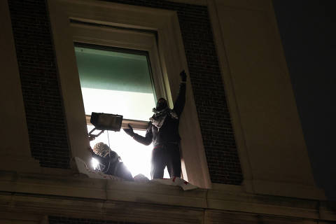 Protesters gesture from a window of Hamilton Hall, after barricading themselves inside the building at Columbia University, after an earlier order from university officials to disband the protest encampment supporting Palestinians, or face suspension, during the ongoing conflict between Israel and the Palestinian Islamist group Hamas, in New York City, U.S., April 30, 2024. REUTERS/Caitlin Ochs ORG XMIT: PPP-CAT001