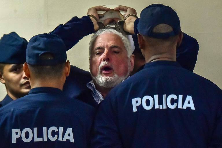 Escoltado pela polícia, o ex-presidente do Panamá Ricardo Martinelli grita à imprensa que seus direitos estão sendo violados 
