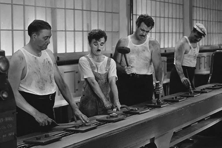 Cena do filme; Chaplin e demais trabalhadores na linha de produção
