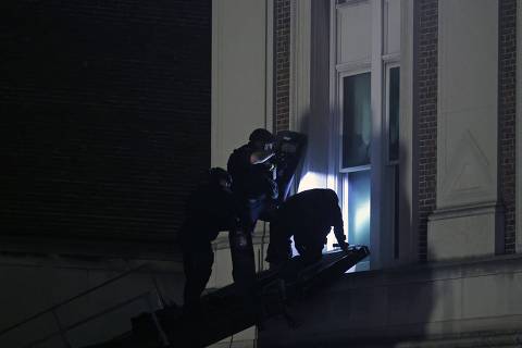 TOPSHOT - NYPD officers in riot gear break into a building at Columbia University, where pro-Palestinian students are barricaded inside a building and have set up an encampment, in New York City on April 30, 2024. Columbia University normally teems with students, but a 