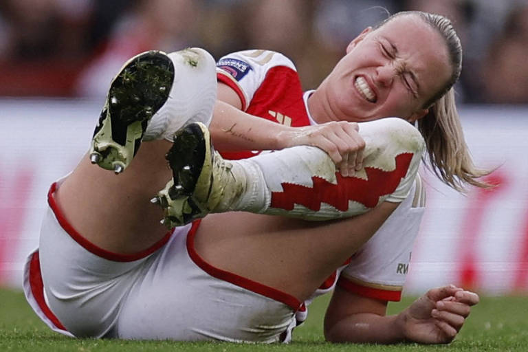 Caída no campo, a atacante Beth Mead, do Arsenal, leva a mão direita à perna esquerda, na altura do joelho, em partida contra o Manchester United em Londres