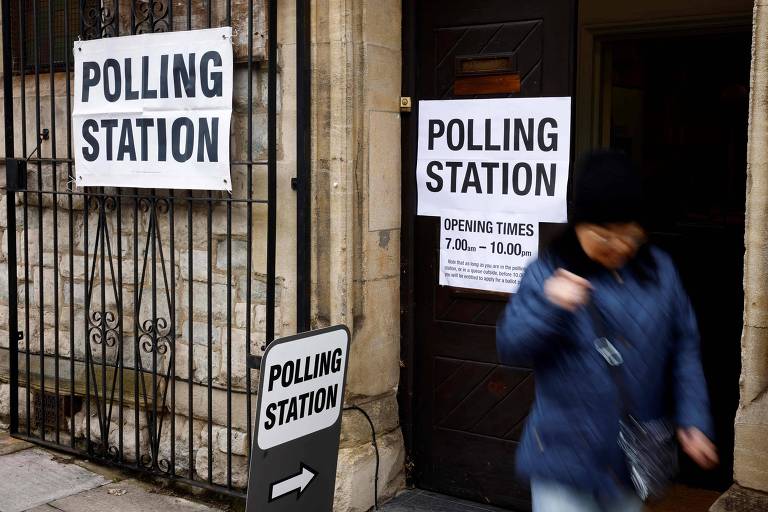 Eleitor branco (imagem um pouco desfocada), com casaco e gorro, sai de local de votação em Londres. Em um cartaz branco, lê-se: Polling station