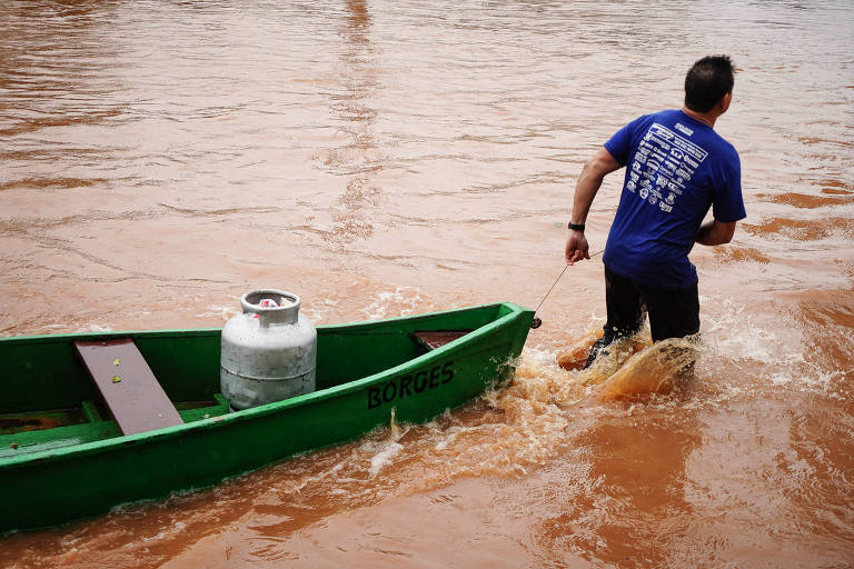 Morador carrega buijão de gás em barco por conta do alagamento