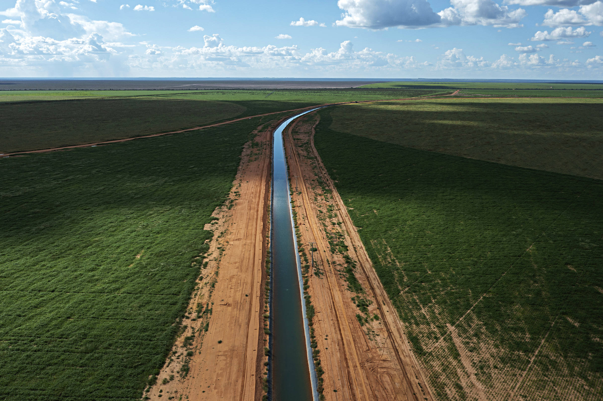 Vista aérea de imenso canal de irrigação que passa entre plantações de soja