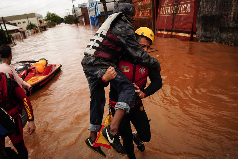 Bombeiro carrega um idoso em área alagada de São Sebastião do Caí durante o aviso de evacuação feito pelo governo gaúcho