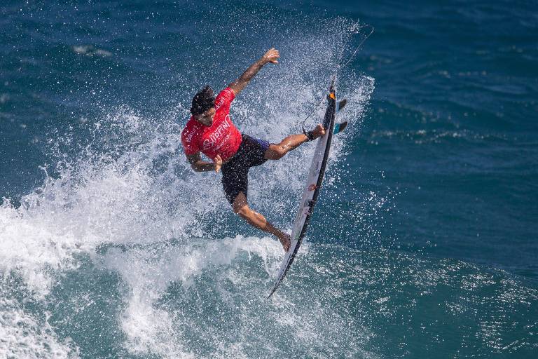 O Surfista Gabriel Medina voa com a sua prancha na tentativa de uma manobra aérea.
