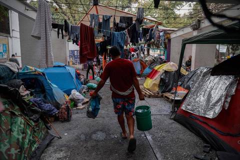 A Venezuelan migrant holds a water pail in a migrant camp in Mexico City, Mexico, on February 14, 2024. 141,000 people sought refuge in Mexico in 2023, a record number. Most were migrants from Haiti, Honduras, and Cuba who work, especially in the often low-paid construction and commerce sectors. (Photo by Rodrigo OROPEZA / AFP)