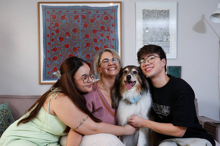 família no sofá (mãe, filha e filho), acompanhados de uma cachorra