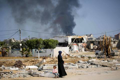 Smoke billows as a woman and child look on amid the rubble of buildings destroyed during Israeli bombardment in Khan Yunis, on the southern Gaza Strip on April 16, 2024, as fighting continues between Israel and the Palestinian militant group Hamas. (Photo by AFP)