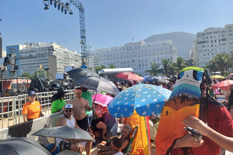 Fãs tentam se proteger do calor na manhã de sábado (4), à espera do show da cantora Madonna em Copacabana, no Rio, bem em frente ao palco
